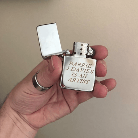 Barrie J Davies Is An Artist Lighter.  This lighter is part of a conceptual art project which I started in 1998 in which the phrase "Barrie J Davies is an Artist" was used to advertise myself as an artist. This text piece is also available on t-shirt's, postcards, socks, mugs, signs, tote bags and other multiple unlimited ephemera. 